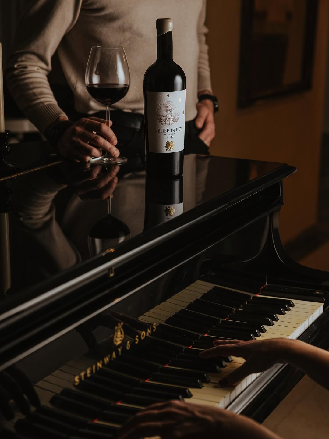 Bottle on Steinway piano with man holding glass - intimate, cinematic